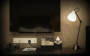 a desk with a lamp and a television on a wall at 1969 Business Suites in Ipoh