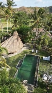 an aerial view of a resort pool with palm trees at Tiki Boutique Hotel Lombok in Selong Belanak