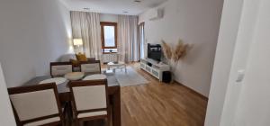 ein Wohnzimmer mit Tisch und Stühlen und einem Fernseher in der Unterkunft Oaza 45 in Belgrad