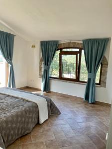 Schlafzimmer mit einem großen Bett und blauen Vorhängen in der Unterkunft Casale Il Fontanello in Todi