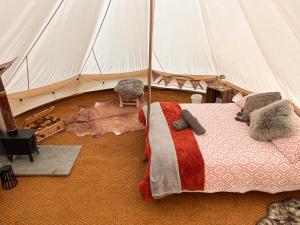 Foulsham的住宿－The Queens Head Glamping，帐篷内一间卧室,配有一张床