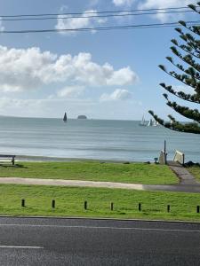 una strada con vista sull'oceano con barche a vela di The Oceanside Motel a Whitianga