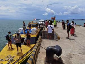 un grupo de personas de pie en un muelle junto a un barco en Gili Ferries ticket en Padangbai