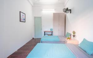twee bedden in een kamer met blauwe lakens bij Tam An Ha Noi Homestay in Hanoi