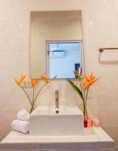 a bathroom with a white sink and a mirror at Kingsacre in Nai Yang Beach