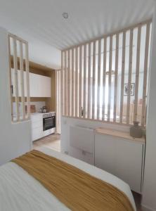 eine weiße Küche mit einem Bett in einem Zimmer in der Unterkunft Le Studio in Saint-Gilles