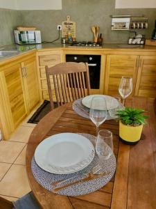 einen Holztisch mit zwei Tellern und Weingläsern in der Unterkunft Ti kaz Grondin in Saint-Joseph