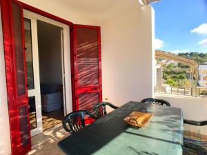 una mesa verde y sillas en un balcón con puerta roja en Villetta Daversa 2 a Torre Vado, en Torre Vado