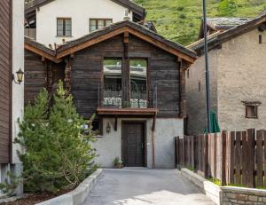 ein Holzhaus mit einer Tür und einem Balkon in der Unterkunft The Cottage by SCHLOSS Zermatt in Zermatt