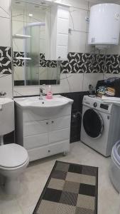 a bathroom with a toilet sink and a washing machine at Apartman AMI in Tuzla