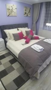 a bedroom with a large bed with pink pillows at Apartman AMI in Tuzla