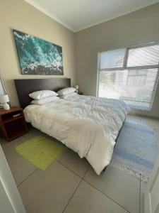 a bedroom with a large white bed and a window at Dolphin Leap 7 in Walvis Bay