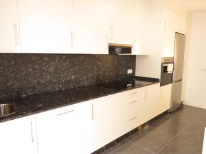 uma cozinha com armários brancos e bancadas pretas em Rua ILLA PANCHA VIVIENDAS USO TURISTICO em Ribadeo