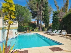 una piscina in un cortile con sedie e alberi di Villa Marguerite a Hyères