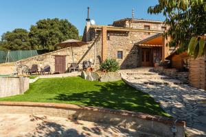a stone house with a yard with a lawn at Masia Can Vilar in Maçanet de la Selva