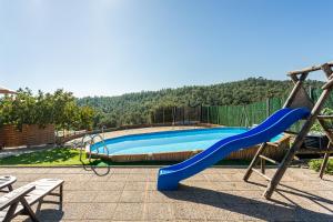 a blue slide in front of a swimming pool at Masia Can Vilar in Maçanet de la Selva
