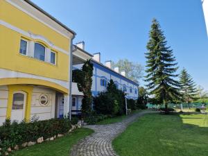 a yellow and blue building with a tree next to it at Rozina Apartman in Mosonmagyaróvár