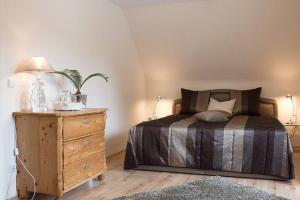 ein Schlafzimmer mit einem Bett und einer Holzkommode in der Unterkunft Harzhaus Romantica in Hahnenklee-Bockswiese
