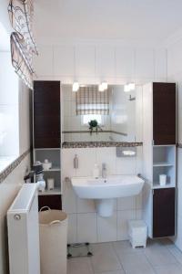 ein weißes Badezimmer mit einem Waschbecken und einem Spiegel in der Unterkunft Harzhaus Romantica in Hahnenklee-Bockswiese