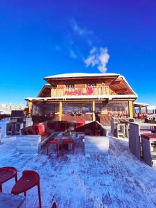 ein Gebäude mit einem Tisch und Stühlen im Schnee in der Unterkunft Berggasthof Platzlalm in Kaltenbach