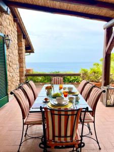 een tafel met stoelen op een patio met uitzicht op de oceaan bij Villa a Cala Piccola in Monte Argentario