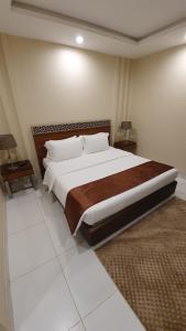1 dormitorio con 1 cama grande y 2 mesitas de noche en منتجع شاطئ الدولفين للإيواء السياحي, en Yanbu