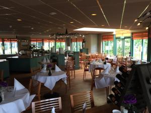een restaurant met witte tafels, stoelen en ramen bij Appartement Baken in Hollum