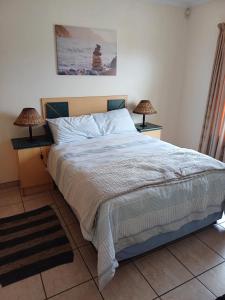 a bedroom with a bed and two lamps on tables at Sunset Sands in Jeffreys Bay