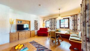 Una sala de estar con una mesa y una silla roja. en Ferienwohnung Geranie, en Oetz