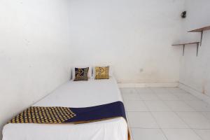 um pequeno quarto branco com uma cama em OYO Life 93153 Kos Jenggala em Tanjung