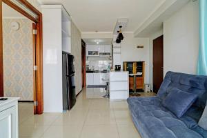 sala de estar con sofá azul y cocina en OYO Life 93097 Apartemen Gateway Pasteur By Kaisar Room, en Bandung