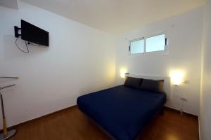 um quarto com uma cama azul e uma televisão de ecrã plano em Confortevole appartamento playa del ingles em Maspalomas