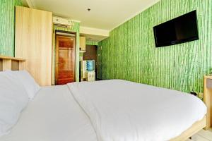 a bedroom with a white bed and a flat screen tv at OYO Life 93065 Apartemen Gateway Pasteur By Glory Rent in Bandung
