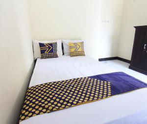 a bed with yellow and blue pillows on it at OYO Life 93155 Wisma Sarah in Tanjung
