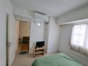 ein Schlafzimmer mit einem Bett und einem TV auf dem Tisch in der Unterkunft OYO Life 93106 Apartement Grand Sentraland By Andi in Karawang