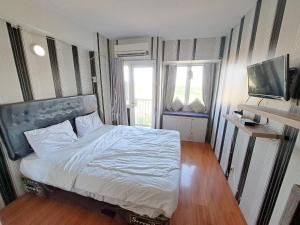 ein Schlafzimmer mit einem großen Bett und einem TV in der Unterkunft OYO Life 93106 Apartement Grand Sentraland By Andi in Karawang