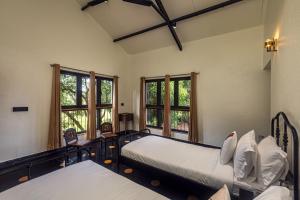 two beds in a room with windows at SaffronStays Amavi Beach House in Dapoli