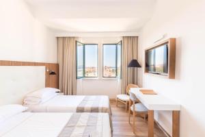 a hotel room with two beds and a desk at Hotel Catalunya in Alghero