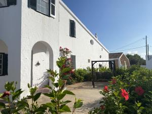 - un bâtiment blanc avec un portail et quelques fleurs dans l'établissement Holiday Home Finca SANT JAUME, à Alaior