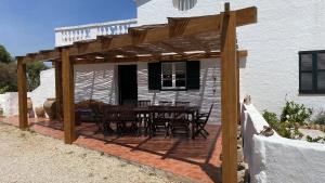 une terrasse avec une table et des chaises sous une pergola en bois dans l'établissement Holiday Home Finca SANT JAUME, à Alaior
