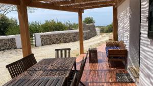 un patio con una mesa de madera, sillas y una pared en Holiday Home Finca SANT JAUME, en Alaior