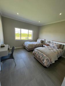 - une chambre avec 2 lits et un bureau dans l'établissement Silwer, à Struisbaai