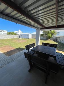 a picnic table and two benches under a pergola at Silwer in Struisbaai