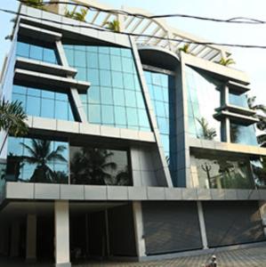 um grande edifício com janelas de vidro e palmeiras em Nakshatra Emerald em Guruvayur