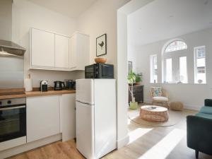 a kitchen with white cabinets and a refrigerator at Seaward in Lyme Regis