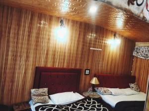 two beds in a room with wood paneling at B ,heritage luxury houseboat in Srinagar