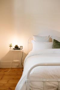 a white bed with a side table next to it at Luxurious terrace home in heart of town in Bendigo