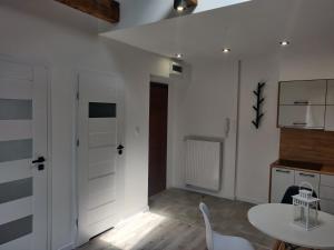 a kitchen with white walls and a table and chairs at Konopnickiej 9 Apartament Loft dostęp na kod in Pabianice