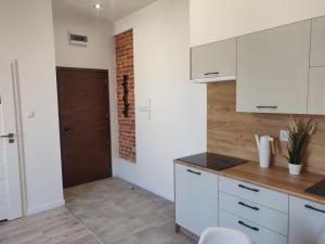 a kitchen with white cabinets and a brick wall at Konopnickiej 9 Apartament Loft dostęp na kod in Pabianice