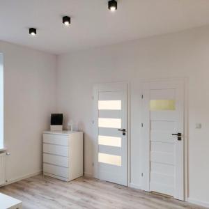 a white room with two sliding doors and a dresser at Konopnickiej 9 Apartament Loft dostęp na kod in Pabianice